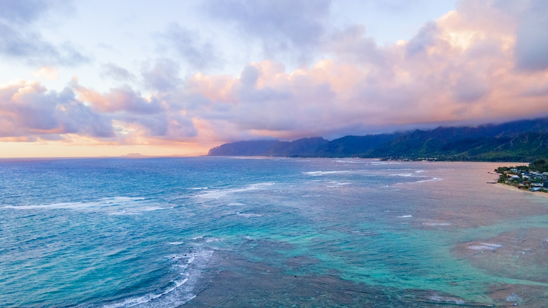Lush green mountains and dramatic coastline of Kauai, Hawaii, seen from above with clouds drifting over ridgelines