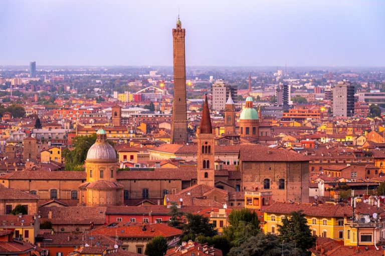 Bologna terracotta rooftops and medieval towers seen from Asinelli Tower at golden hour