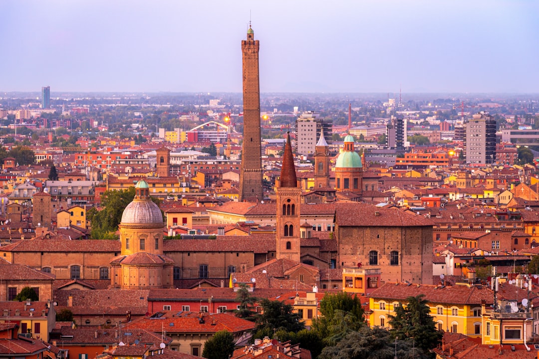 Bologna terracotta rooftops and medieval towers seen from Asinelli Tower at golden hour