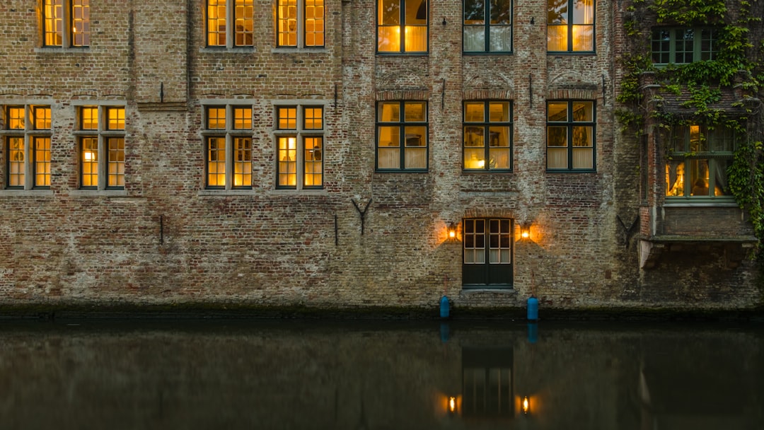 Canal-side boutique hotel facade in Bruges Belgium with ivy and arched windows