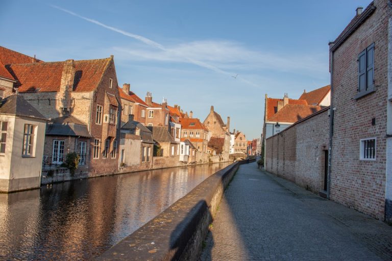 Early morning view of Groenerei canal in Bruges Belgium with medieval gabled houses reflected in still water