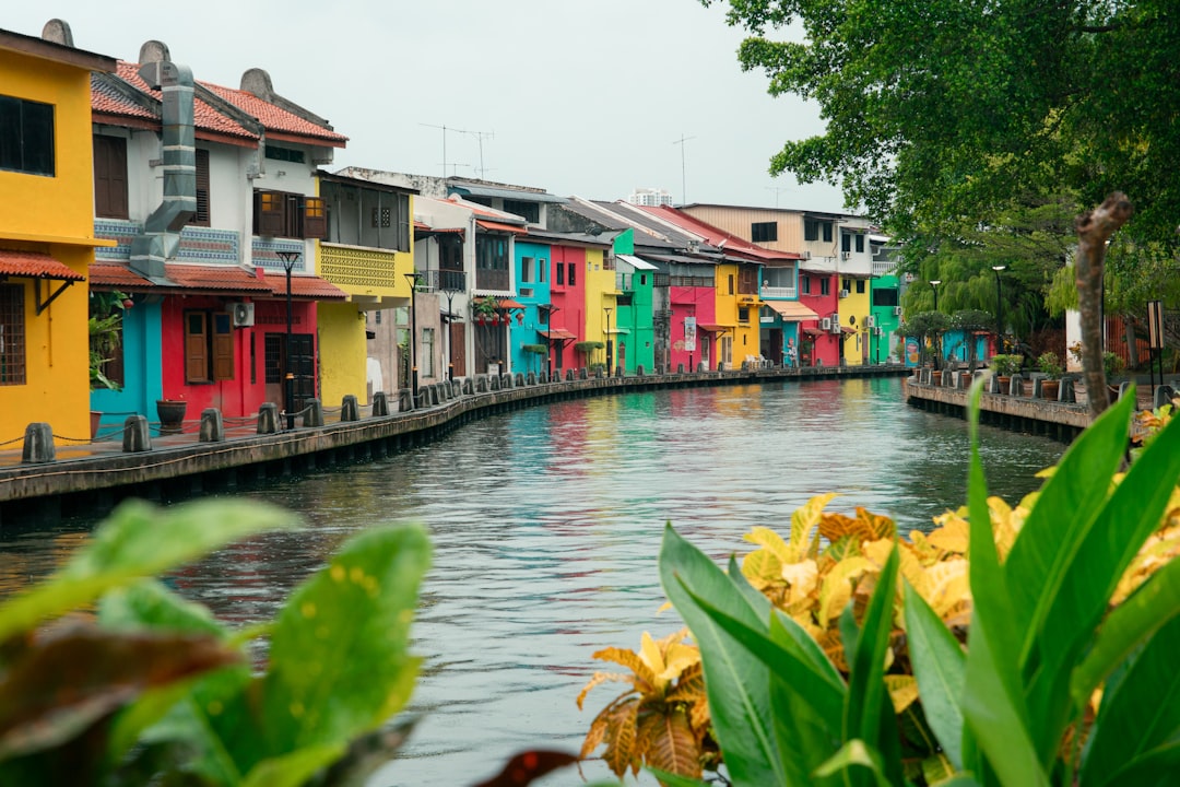 Malacca River at dusk with illuminated street art murals and a tourist boat