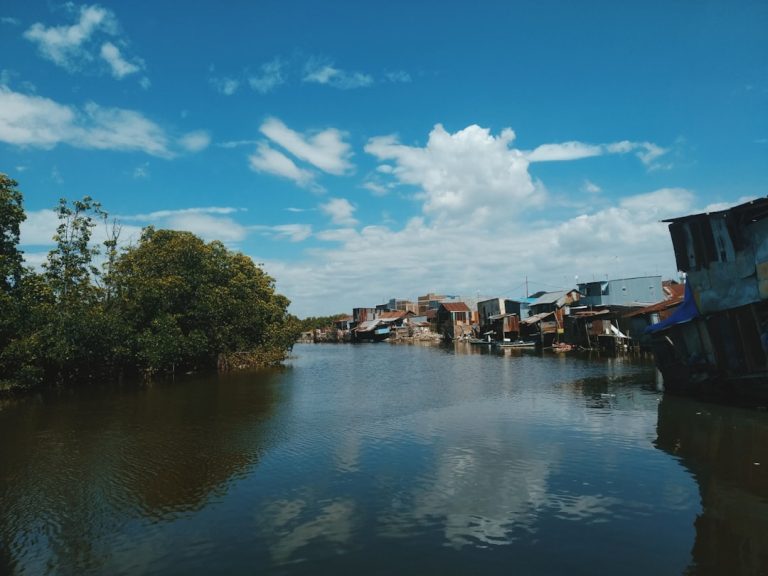 Malacca River lined with colorful colonial shophouses and a tourist boat at golden hour