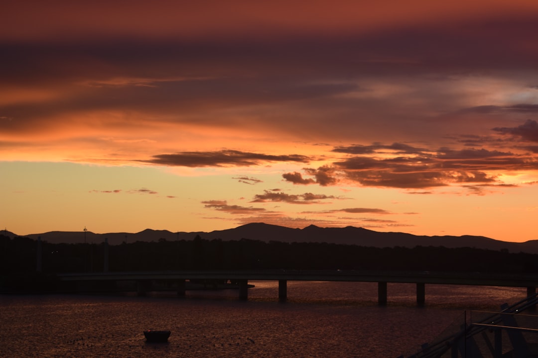 Lake Burley Griffin at golden hour with Parliament House and autumn trees along the Canberra foreshore
