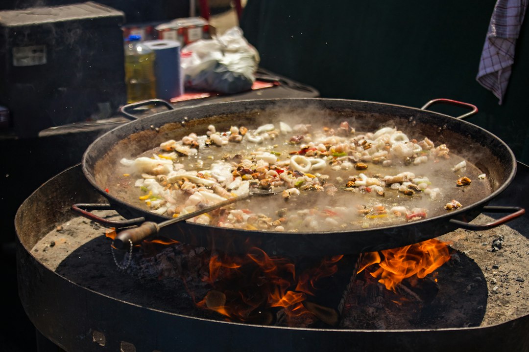 Traditional paella Valenciana cooking over wood fire with socarrat crust