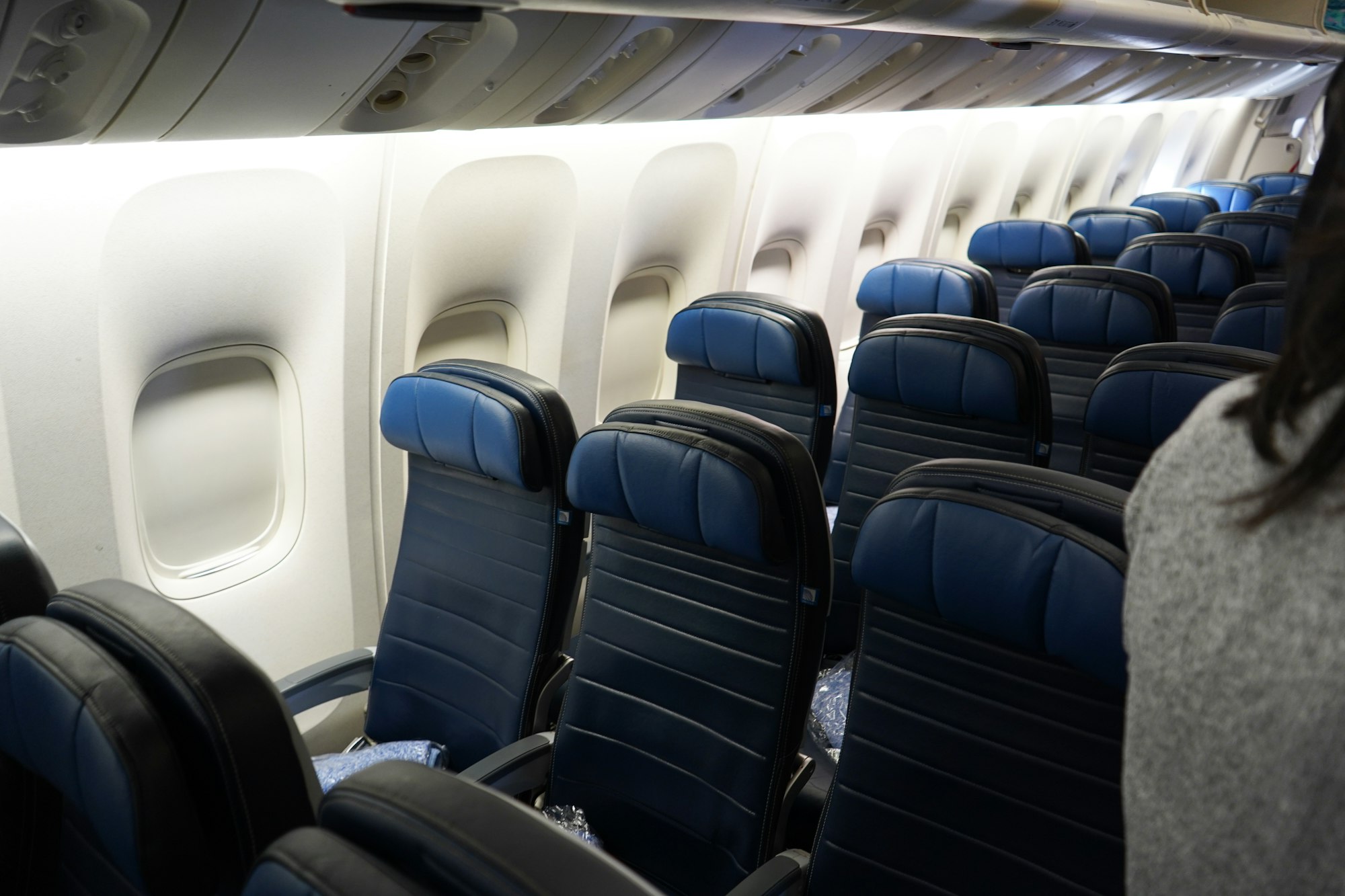 Rows of blue leather seats in an airplane cabin beside the window panels