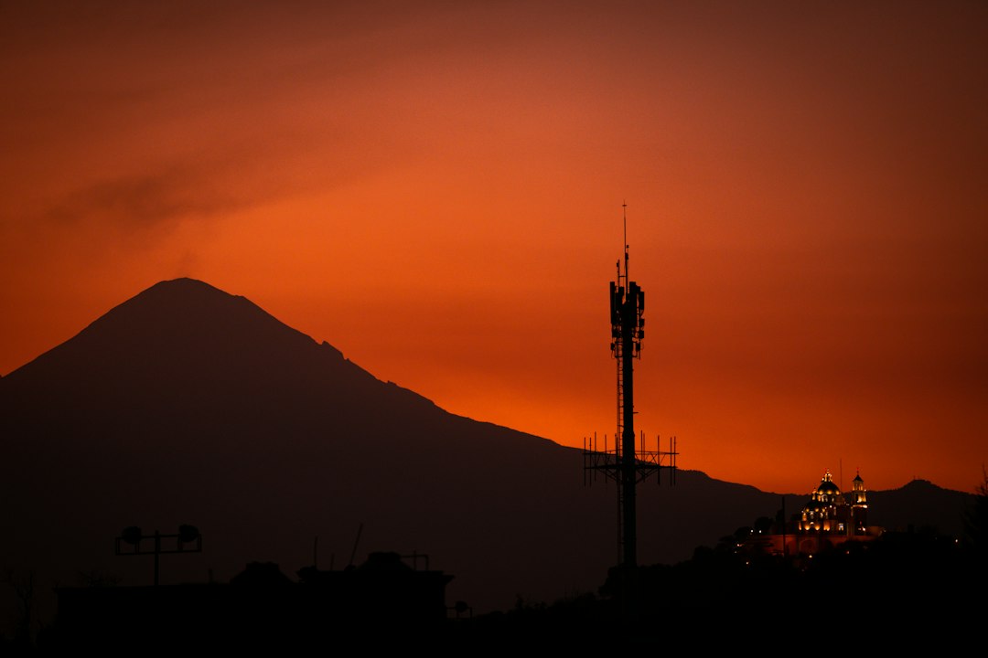 A tall tower sitting on top of a lush green hillside in Cholula, Mexico