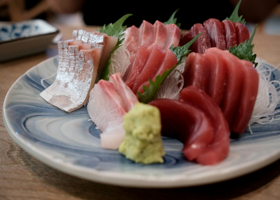 Assorted sashimi slices with wasabi on a patterned ceramic plate