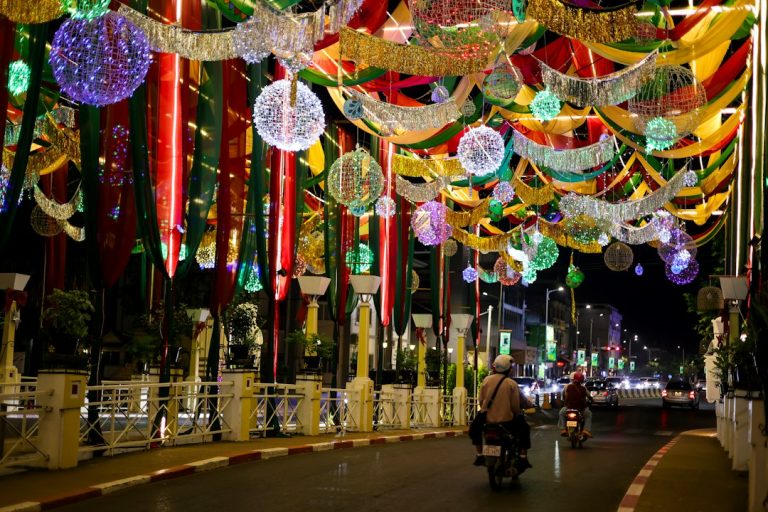 A person riding a motorcycle down a street covered in lights in Siem Reap, Cambodia