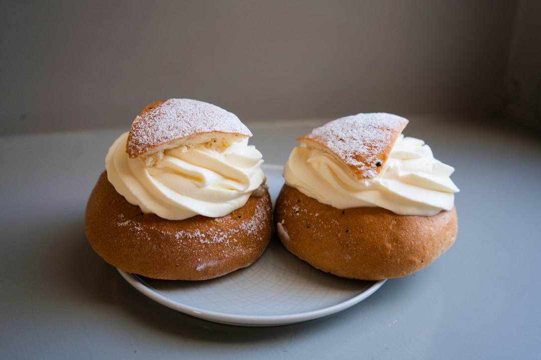 Halved cardamom bun filled with whipped cream and almond paste beside a cup of coffee