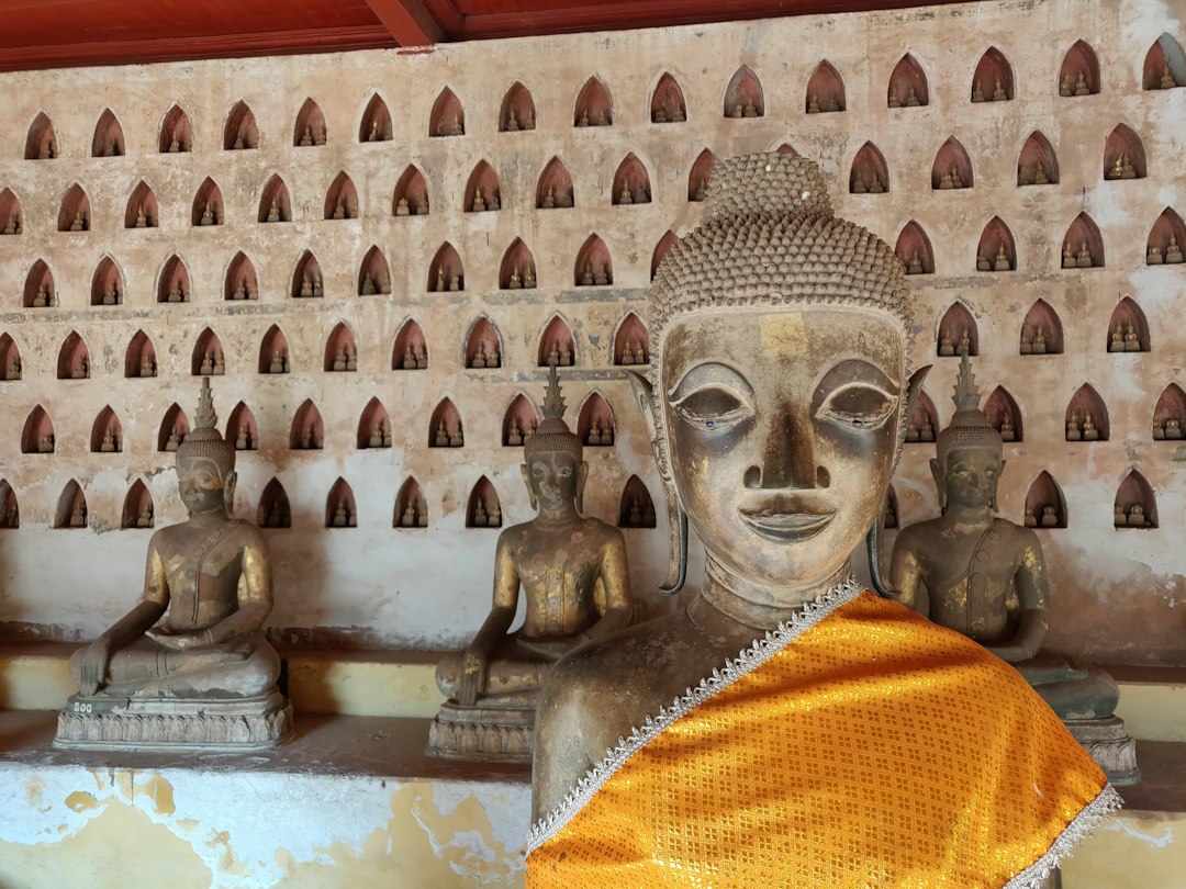 Gold buddha statue in front of white concrete wall in Vientiane, Laos