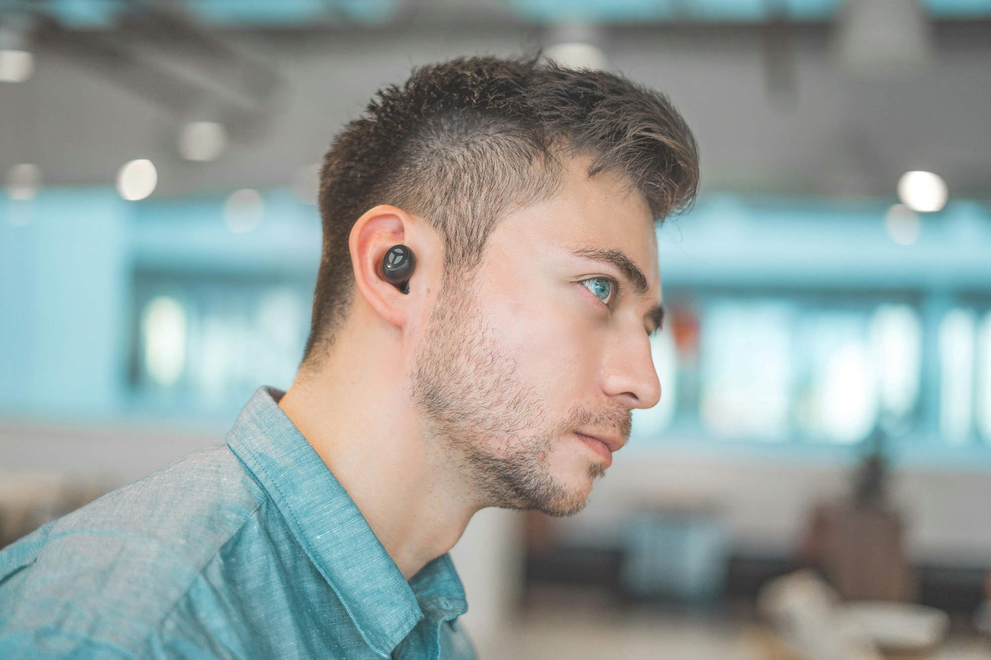 Man in profile wearing a small black wireless earbud in his ear